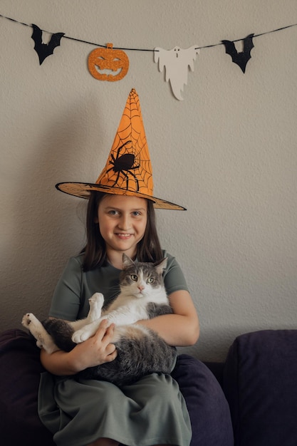Dziewczyna w pomarańczowym kapeluszu z kotem, koncepcja halloween