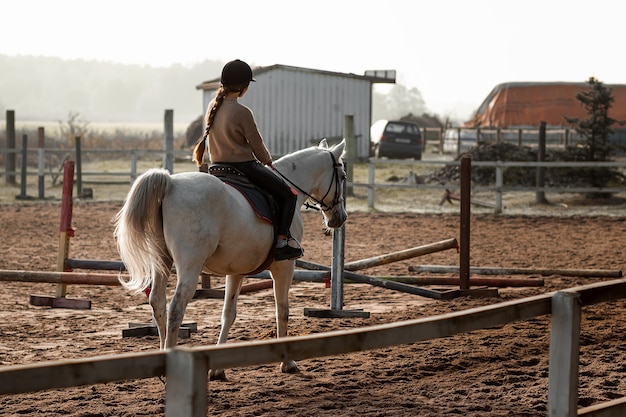 Dziewczyna w postaci dżokeja jeździ konno po hipodromie. Lekcje jazdy konnej, jazda konna.