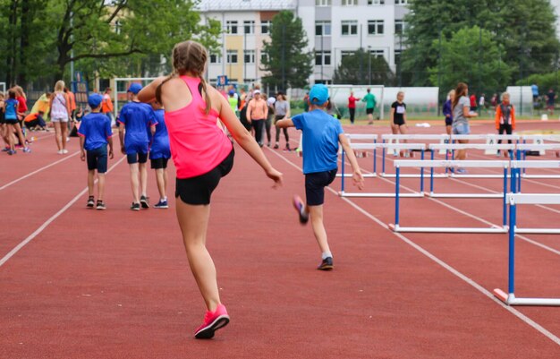 Dziewczyna w różowej koszulce na treningu robi skok w lekkoatletyce