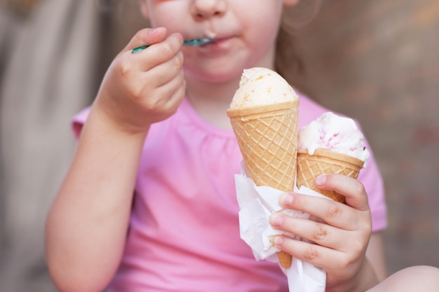 Dziewczyna w różowej sukience jedząca lody w czasie upałów