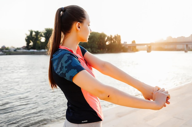 Dziewczyna w sportowym stroju rozgrzewa się przed wieczornym joggingiem