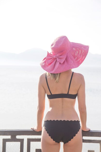 Dziewczyna w strój kąpielowy i kapelusz nad morzem.