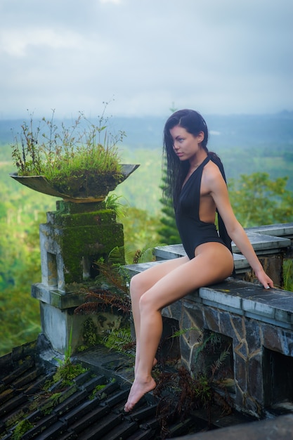Dziewczyna w stroju kąpielowym w mistycznym opuszczonym zgniłym hotelu na Bali z błękitnym niebem.