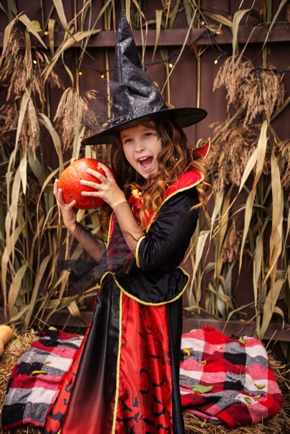 Zdjęcie dziewczyna w stroju wiedźmy rzuca magię na dynię na halloween