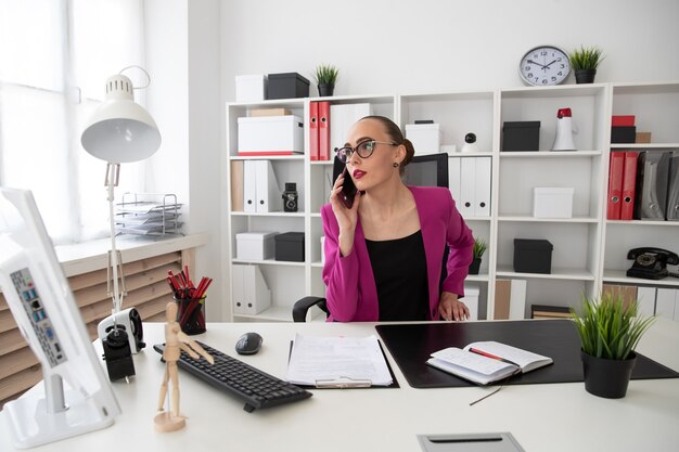 Dziewczyna w stylu biznesowym rozmawia przez telefon w biurze