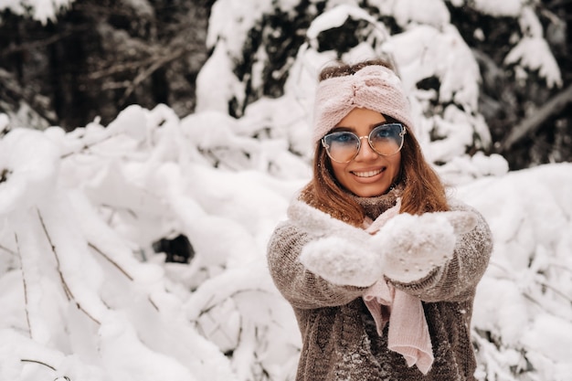 Dziewczyna w swetrze i okularach zimą w zaśnieżonym lesie