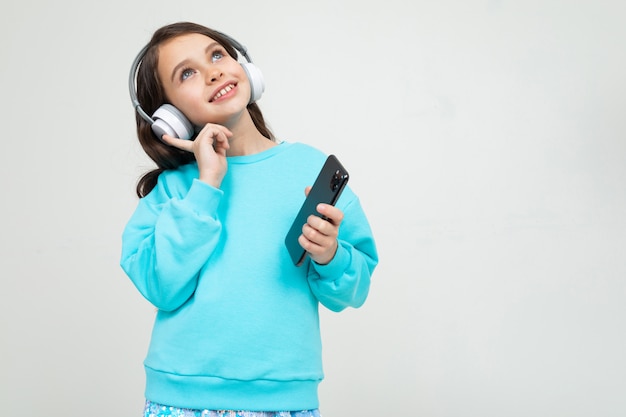 Dziewczyna w turkusowej bluzce relaksuje się przy muzyce w słuchawkach