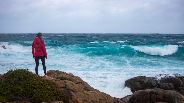 dziewczyna w warkoczach obserwuje ogromne fale podczas burzy nad oceanem w zachodniej australii