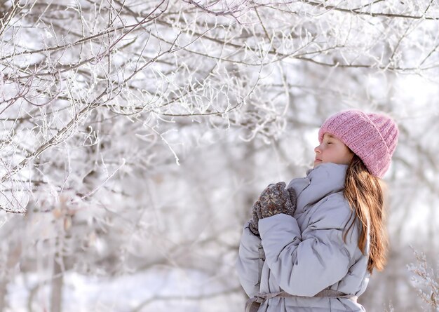 dziewczyna w wieku szkoły podstawowej stoi w zimowym lesie