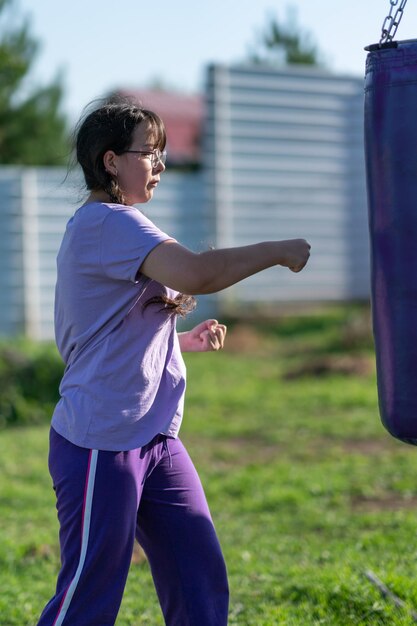 Dziewczyna w worku z piaskiem. Trening bokserski Muaythai. Zdrowa dziewczyna wbijania w worek bokserski.