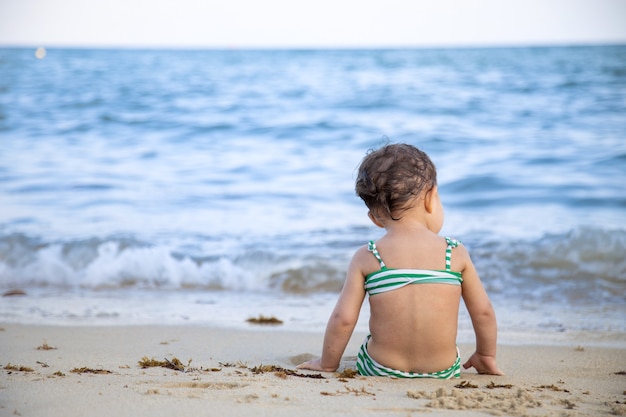 Dziewczyna W Zielonym Stroju Kąpielowym Siedzi Na Brzegu Piaszczystej Plaży