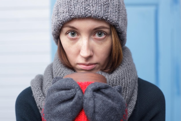 Zdjęcie dziewczyna w zimowej czapce i szaliku pije gorący napój, aby się ogrzać