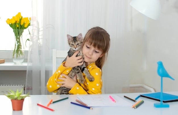 Dziewczyna w żółtej sukience rysuje kredkami w swoim pokoju przy biurku, obok niej w domu, obok niej w domu, Koncepcja kreatywności i rozwoju dzieci Selektywne skupienie