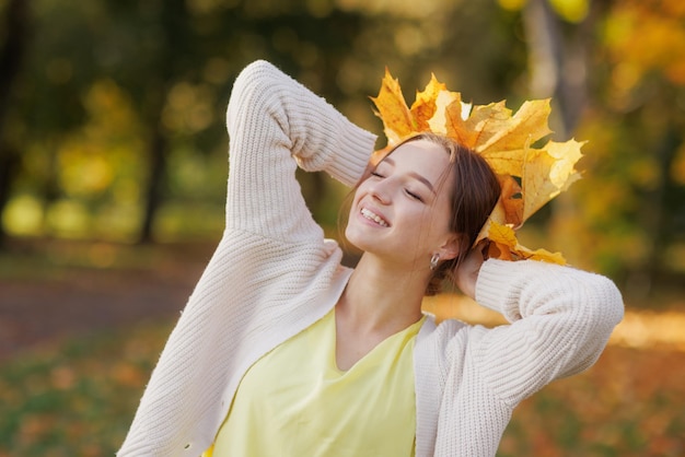 dziewczyna w żółtych ubraniach w jesiennym parku raduje się jesienią trzymając w rękach żółte liście