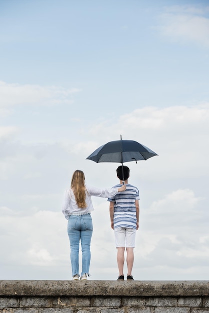 Dziewczyna wspierająca chłopaka za pomocą parasola