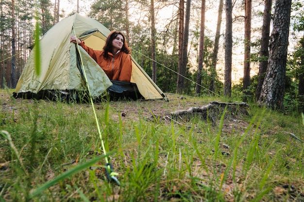 Dziewczyna wychodzi z namiotu po spaniu. Wyjedź poza miasto w lesie. Kemping.