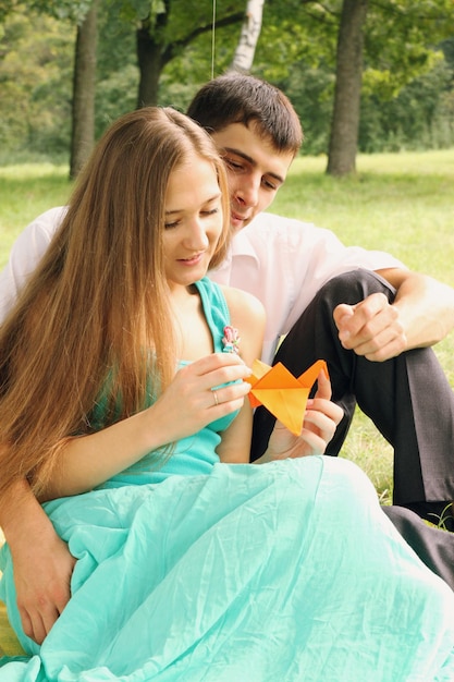 Dziewczyna wyciąga żurawia z papieru w parku