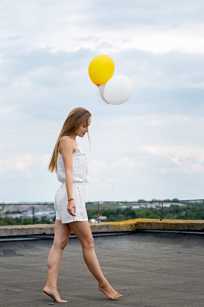 Zdjęcie dziewczyna z balonami na dachu domu