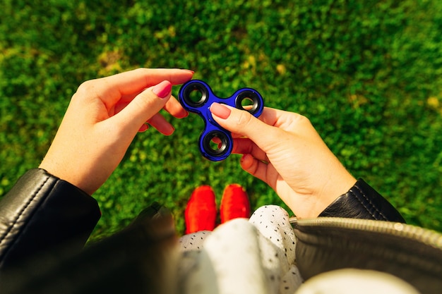 Dziewczyna z czerwonymi trampkami bawić się Fidget Spinner w rękach, koncepcja łagodzenia stresu