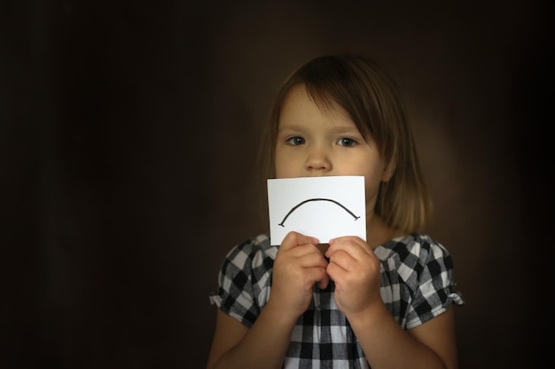 Zdjęcie dziewczyna z kartonowym smutkiem koncepcja emocji i dzieciństwa