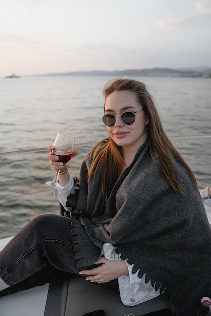 Dziewczyna z kieliszkiem czerwonego wina na jachcie podczas rejsu statkiem