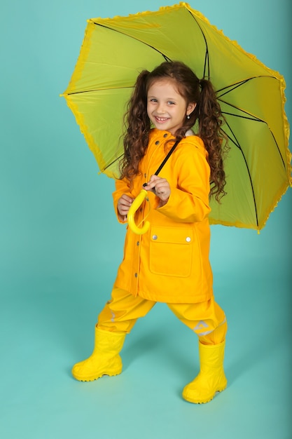 dziewczyna z kręconymi włosami w żółtej kurtce nosi kombinezon z żółtym parasolem w dłoniach