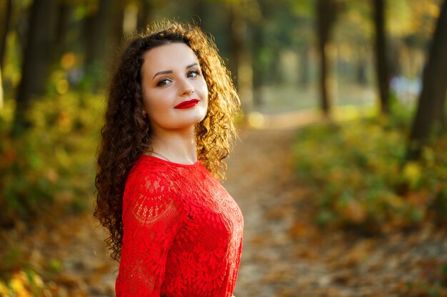 Dziewczyna z lokami w czerwonej sukience w jesiennym lesie