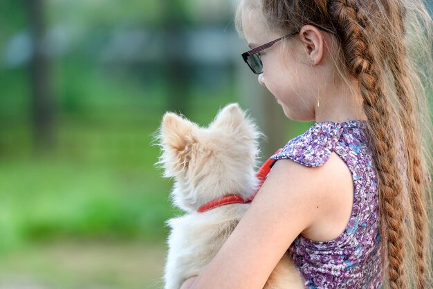 Dziewczyna z małym psem na ramieniu, widok z tyłu