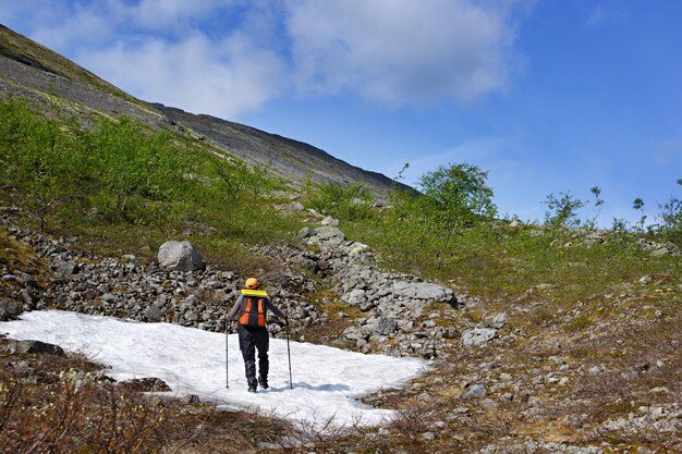 Dziewczyna z plecakiem i kijami trekkingowymi stoi na lodowcu górskim.