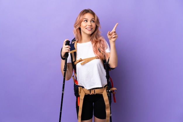 dziewczyna z plecakiem i kijkami trekkingowymi na na białym tle fioletowym wskazującym palcem wskazującym to świetny pomysł