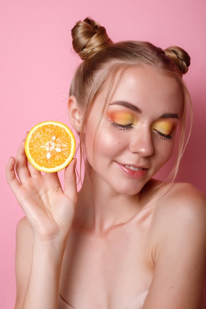 Dziewczyna z pomarańczowym i letnim makijażem na różowym tle
