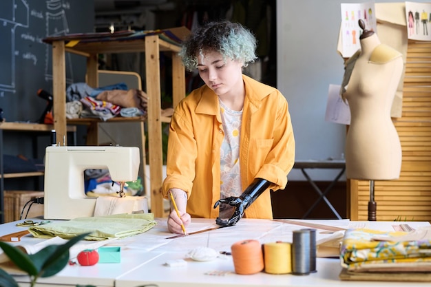 Dziewczyna z protetyczną ręką szyjąca ubrania w atelierze