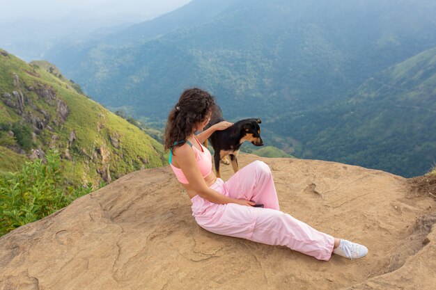 Dziewczyna z psem ciesząca się górską scenerią na skraju urwiska