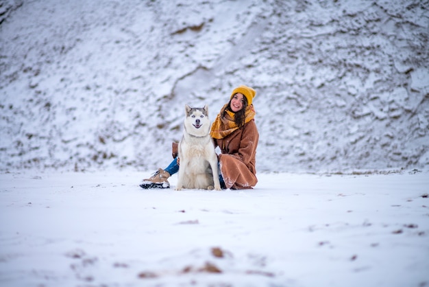 Dziewczyna z psem rasy husky stoi w winter park