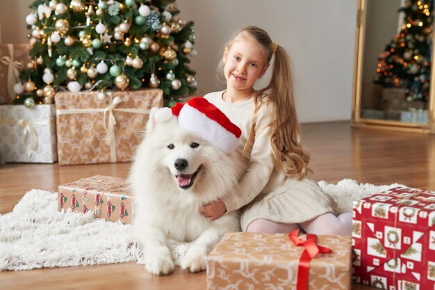 Dziewczyna z psem w pobliżu choinki na scenie Bożego Narodzenia
