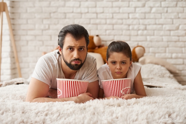 Dziewczyna z tatą jedz popcorn z niezrozumieniem.