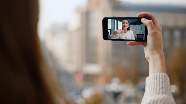 Dziewczyna z ulicy wideo dzwoniąc do przyjaciela z bliska uśmiechnięta kobieta machająca ekranem smartfona