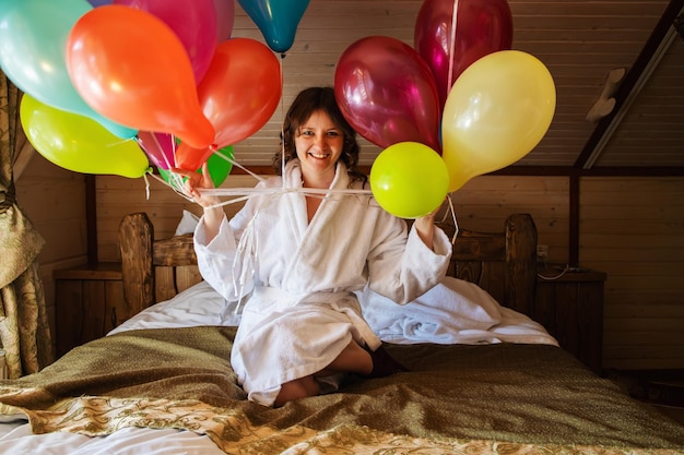 Zdjęcie dziewczyna z urodzinami z balonami na łóżku rano