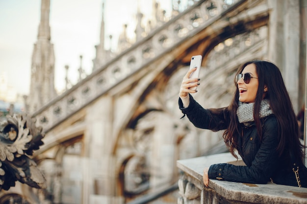 dziewczyna za pomocą swojego telefonu podczas zwiedzania duomo w Mediolanie we Włoszech