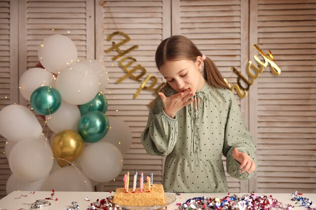 Dziewczyna zdmuchuje świeczki na urodzinowym torcie