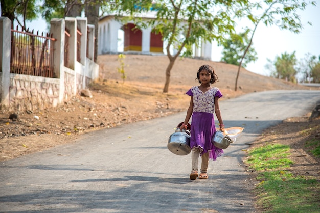 Dziewczyna ze wsi idzie po wodę pitną ze studni.