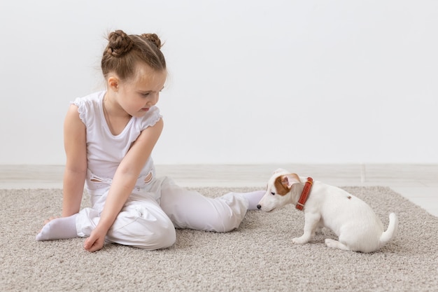 Dziewczynka bawi się swoim szczeniakiem Jack Russell Terrier w pomieszczeniu