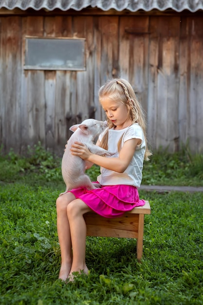 Dziewczynka bawi się ze świnią na podwórku domu Dzieci opiekują się zwierzętami