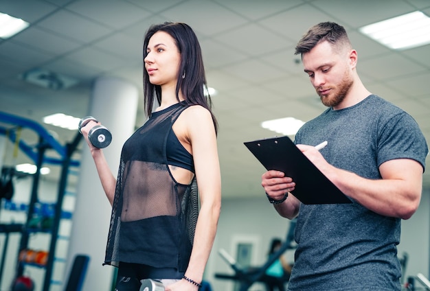 Dziewczynka fitness mająca trening siłowy z pomocą trenera na siłowni Osobisty instruktor fitness Trening osobisty