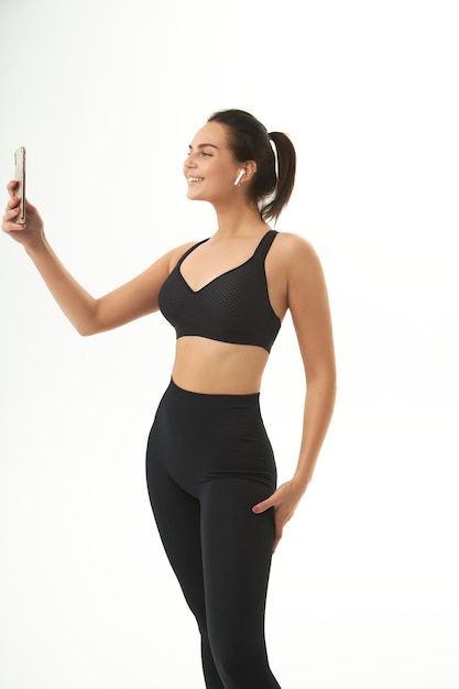 Dziewczynka fitness na treningu w odzieży sportowej trzyma w dłoniach inteligentny telefon