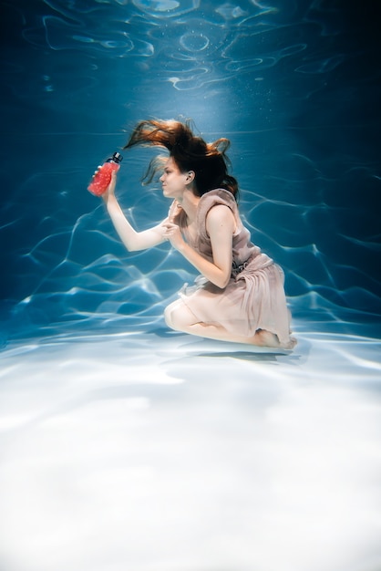 Zdjęcie dziewczynka fitness z kolorowym smoothie. świeżość pod wodą, pływanie i nurkowanie.