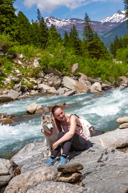 Zdjęcie dziewczynka gra z psem husky na brzegu rzeki górskiej