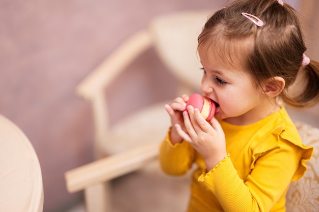 Dziewczynka je pyszne smaczne słodkie kolorowe macaron