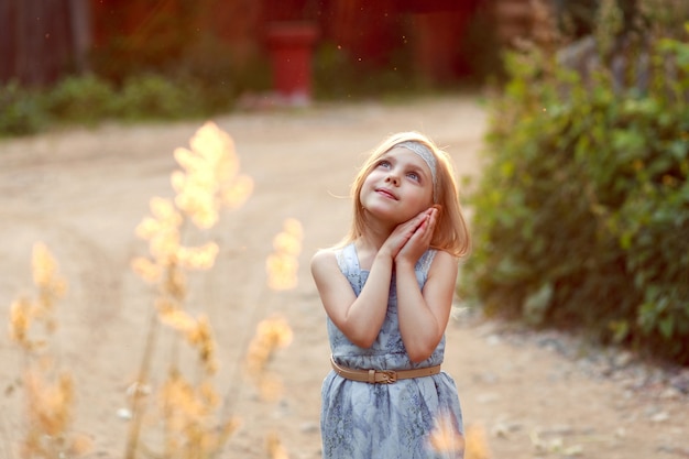 Zdjęcie dziewczynka o zachodzie słońca w niebieskiej sukience boso