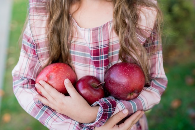 dziewczynka trzymająca świeże organiczne czerwone jabłka
